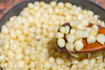 Closeup pot full of cooked corn with wooden spoon scooping up