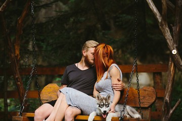 beautiful couple together with dog on a swing