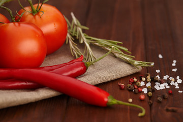 Fresh tomatoes, peppers, herbs and spices on wooden table