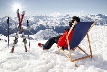 Women at mountains in winter lies on sun-lounger - obrazy, fototapety, plakaty