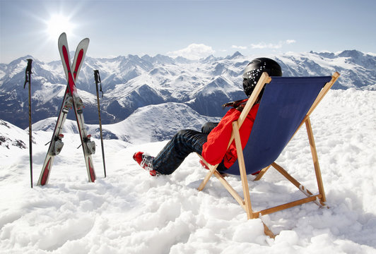 Women at mountains in winter lies on sun-lounger