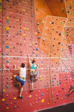 Couple climbing up rock wall