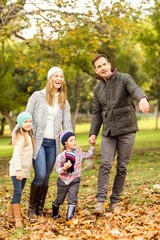 Fototapeta premium Smiling young family walking in leaves