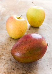 Apples and mango on rustic wooden board