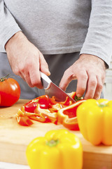 Close up of male hands cutting red pepper on cutting board at home