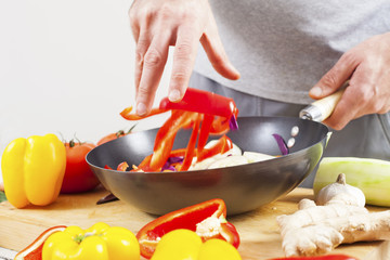 Close up of man hands adding red pepper to wok