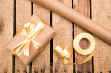 Nicely wrapped presents in brown and golden wrapping on wooden