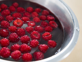 Raspberries in a stainless steel bowl filled with water