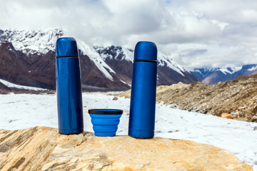 Two Blue travel thermoses Thermo Bottles and Cup on stone