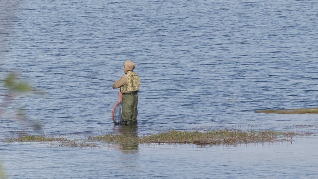 Fisherman catches fishes in the lake near the shore