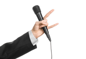 Business and speech topic: Man in black suit holding a black microphone isolated on white background in studio