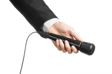 Business and speech topic: Man in black suit holding a black microphone isolated on white background in studio