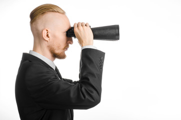 Fototapeta premium Business and search topic: Man in black suit holding a black binoculars in hand on white isolated background in studio