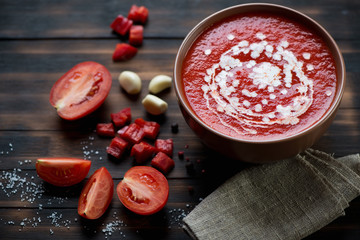 Bowl with tomato soup gazpacho, rustic wooden background