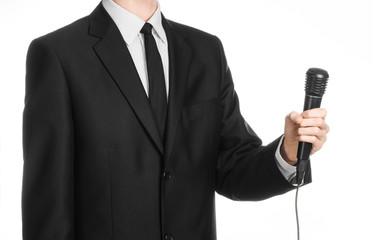 Naklejka premium Business and speech topic: Man in black suit holding a black microphone isolated on white background in studio