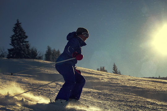 Girl skier slade down on the snow hill in bright sun backlight