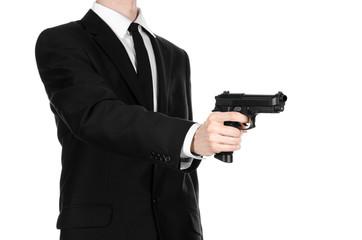 Firearms and security topic: a man in a black suit holding a gun on an isolated white background in studio