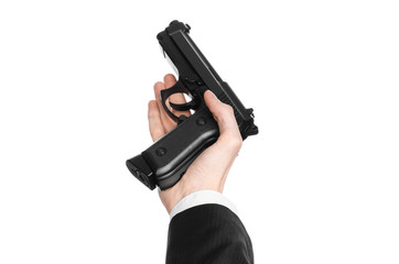 Firearms and security topic: a man in a black suit holding a gun on an isolated white background in studio