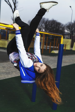 Young girl hanging upside down on the playground