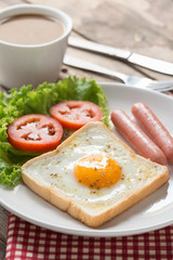 Fried toast with egg, sausage and a cup coffee.