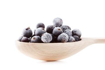 Frozen black currant in a wooden spoon