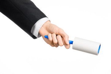 Dry cleaning and business theme: a man in a black suit holding a blue sticky brush for cleaning clothes and furniture from dust isolated on white background in studio.