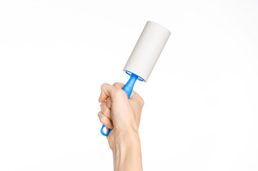 Clean clothes and cleaning the house topic: human hand holding a blue sticky brush for cleaning clothes and furniture from dust isolated on white background in studio.