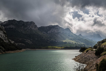 verwunschener, grün leuchtender See vor aufziehendem Gewitter