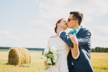 groom kissing bride in field