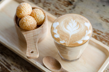 A glass of hot latte art coffee and candy eggs swan