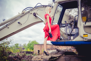 The blonde in a red dress on the excavator, beauty fashion, autumn