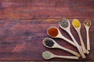 Wooden spoons full of aromatic herbs and spices on a wooden cutting board
