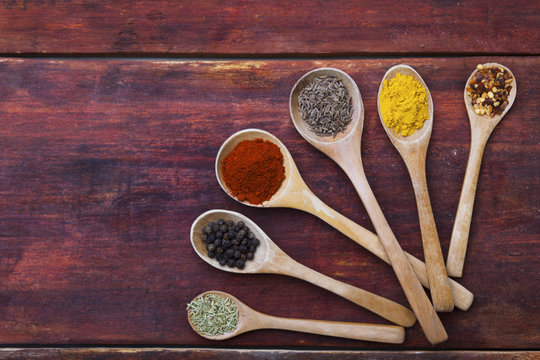 Wooden spoons full of aromatic herbs and spices on a wooden cutting board