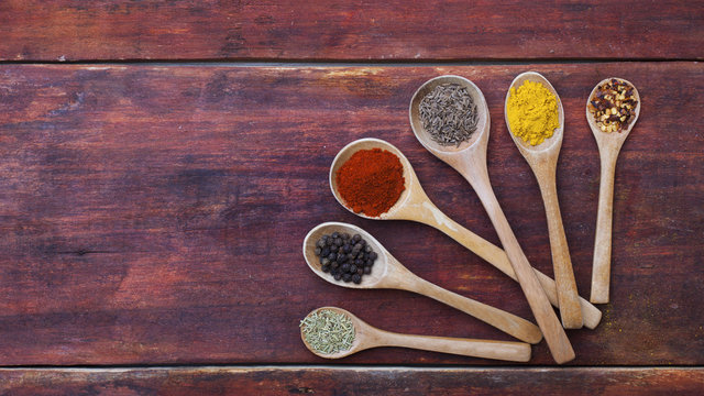 Wooden spoons full of aromatic herbs and spices on a wood cuttin