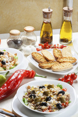 Delicious tuna salad with various vegetables and toast bread arranged on the table with fresh garlic, peppers, tomatoes, spices and seasoned oil.