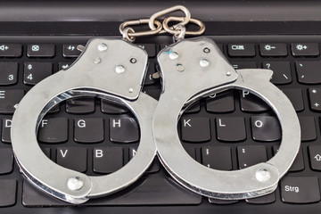 Handcuffs on keyboard, symbolizing computer security and police investigation