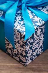 Vintage christmas gift box with blue bow on wooden surface