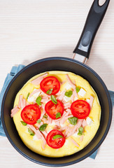 omelet with ham and cheese in a frying pan