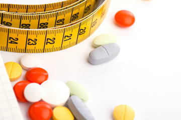 Pills, notepad and measuring tape on the white table
