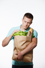 Portrait of positive young male, holding package with fresh food