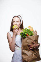 Young woman holding grocery shopping bag with vegetables