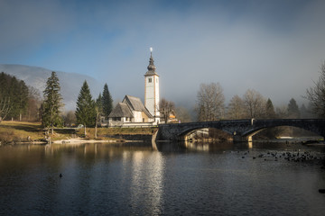 Majestic colorful foggy morning scene in the Triglav national park, located in the Bohinj Valley of the Julian Alps.View of the church St. John the Baptist. Slovenia, Europe