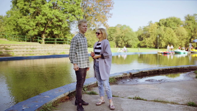 Couple standing in the park next to the river and chatting
