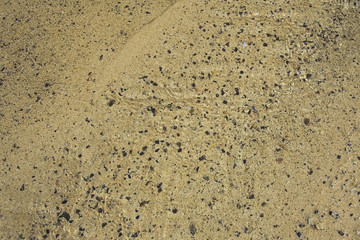 Brook on the sand beach low water. Rolling grains. Background like the aquarium. Orzola bay, Lanzarote, Canary Islands