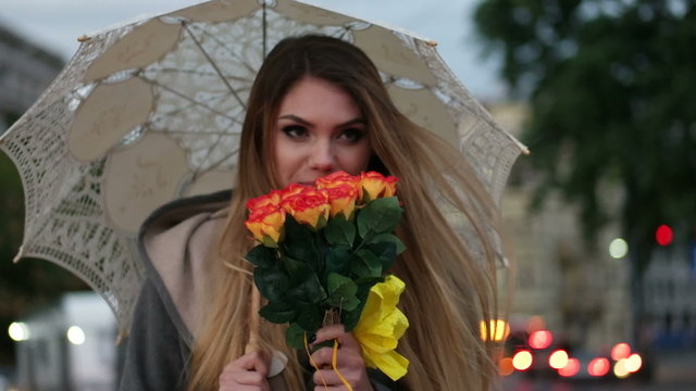 blonde woman holding a bunch of roses in a rainy day 