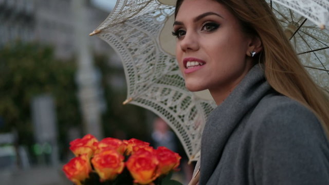 blonde woman holding a bunch of roses in a rainy day 