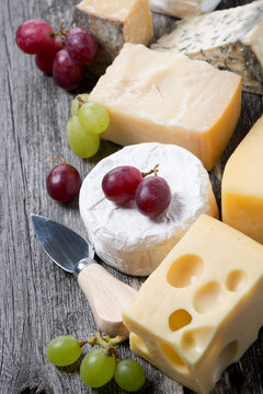 assortment of cheeses and grapes on a wooden background