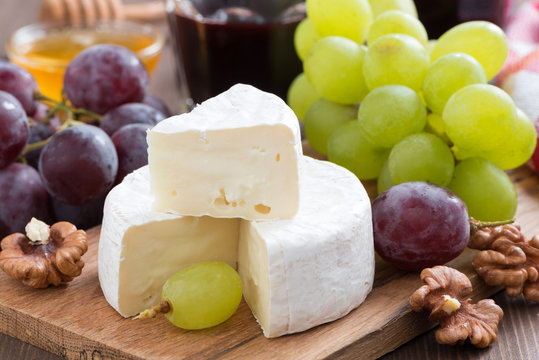 fresh camembert on a wooden board and grapes