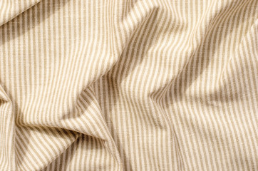 Striped brown and beige textile pattern as a background. Close up on crumpled material texture fabric.