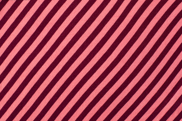 Striped pink and red textile pattern as a background. Close up on diagonal stripes material texture fabric.
